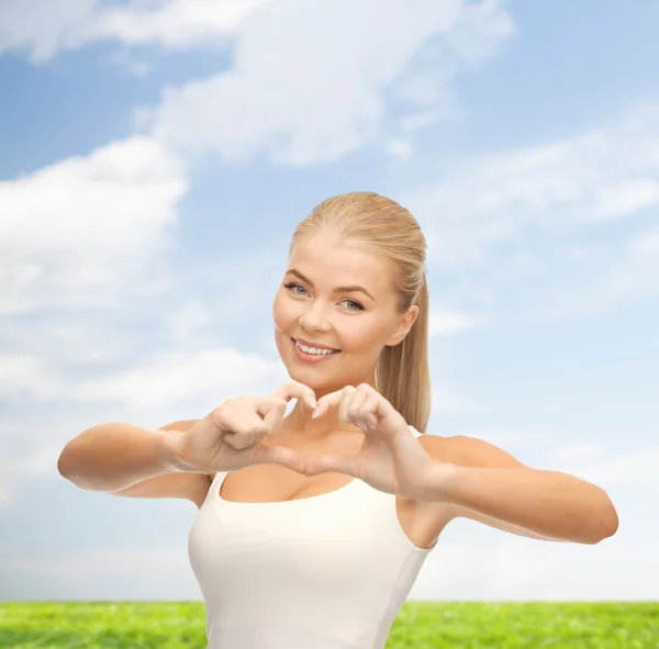 Usmívající se žena ukazující gesto tvar srdce — Stock fotografie