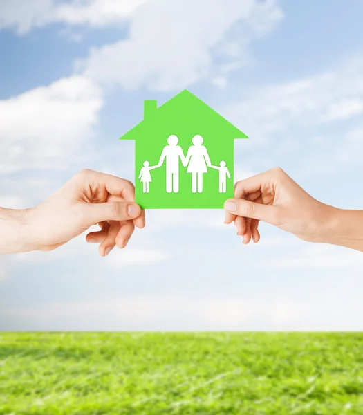 Hands holding green house with family — Stock Photo, Image