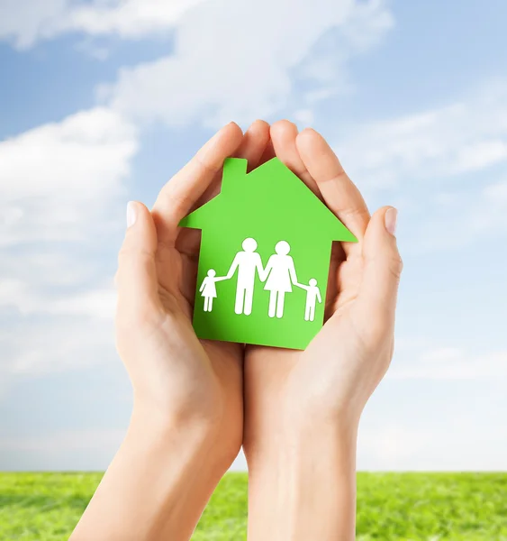 Manos sosteniendo casa verde con la familia —  Fotos de Stock