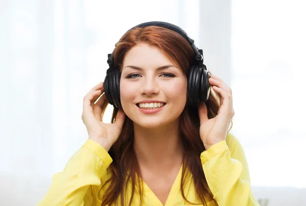 Sorrindo menina em fones de ouvido em casa — Fotografia de Stock