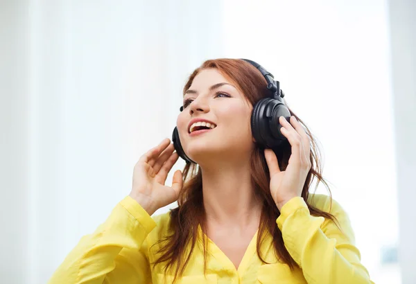 Sorridente ragazza in cuffia a casa — Foto Stock