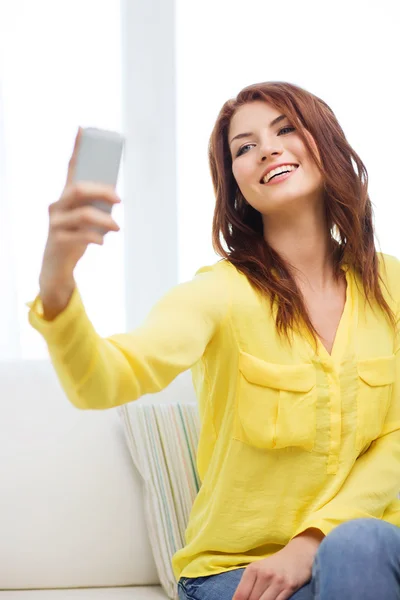 Улыбающаяся женщина со смартфоном дома — стоковое фото