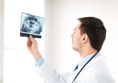 Male doctor or dentist looking at x-ray clipart