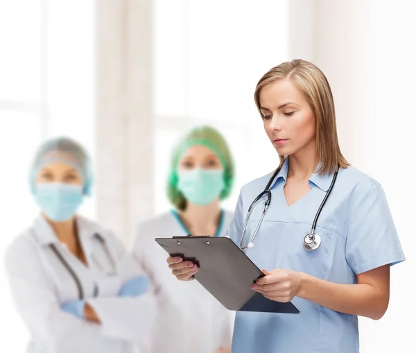 Médico o enfermera sonriente con portapapeles — Foto de Stock