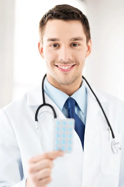 Joven médico masculino con un paquete de pastillas — Foto de Stock