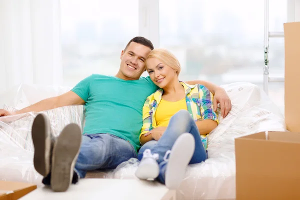 Улыбающаяся пара отдыхает на диване в новом доме — стоковое фото