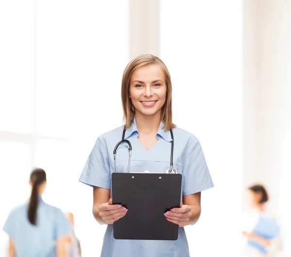 Улыбающаяся женщина-врач или медсестра с планшетом — стоковое фото