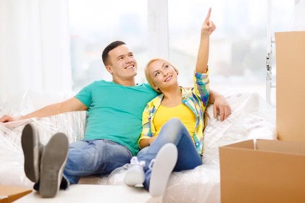 Casal sorridente relaxante no sofá em nova casa — Fotografia de Stock