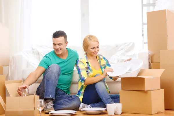 Smiling couple unpaking boxes with kitchenware — Stock Photo, Image