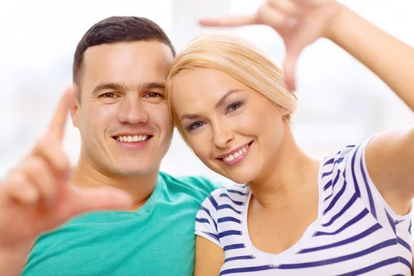 Sorrindo casal feliz fazendo gesto quadro em casa — Fotografia de Stock