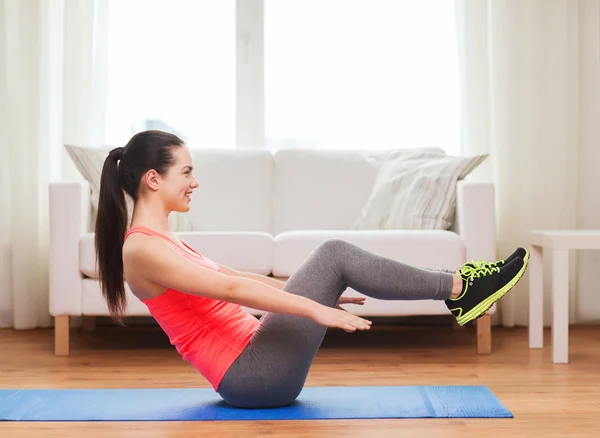 Smiling girl doing exercise on floor at home — Stock Photo, Image