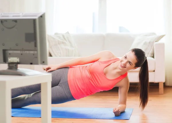 Smiling teenage girl doing side plank at home — Stock Photo, Image