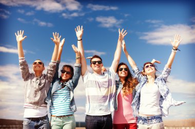 Group of smiling teenagers holding hands up clipart