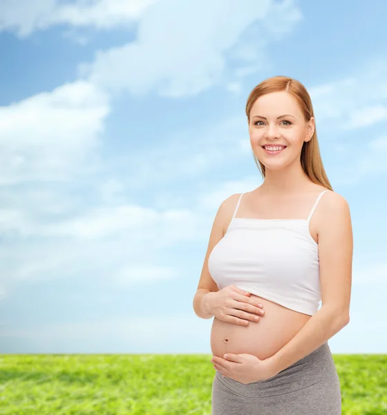 Glückliche zukünftige Mutter, die ihren Bauch berührt — Stockfoto