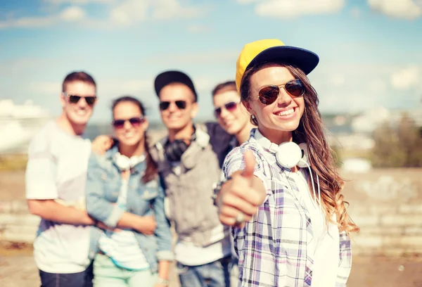 Adolescente chica con auriculares y amigos fuera — Foto de Stock