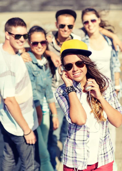 Tonårsflicka med hörlurar och vänner utanför — Stockfoto