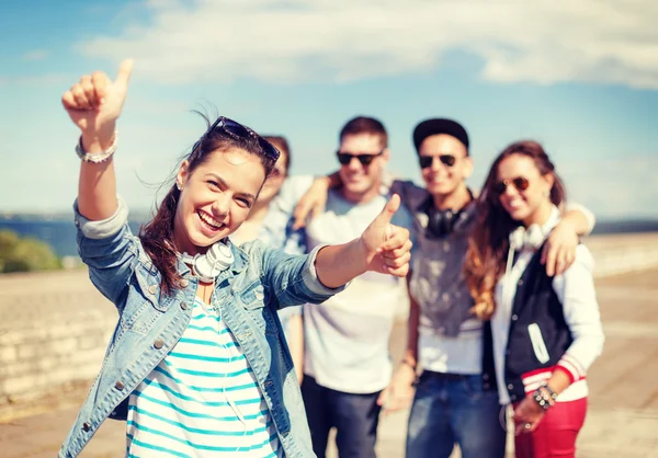 Teenage girl with headphones and friends outside — Stock Photo, Image