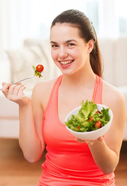 Adolescente souriante avec salade verte à la maison — Photo