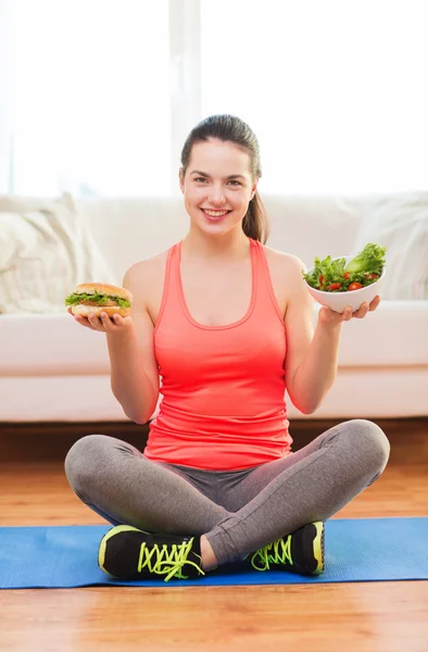 Lachende tiener met groene salade en hamburger — Stockfoto