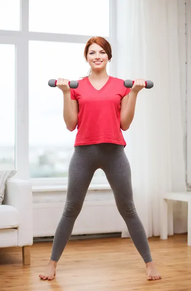 Sonriente adolescente haciendo ejercicio con mancuernas — Foto de Stock
