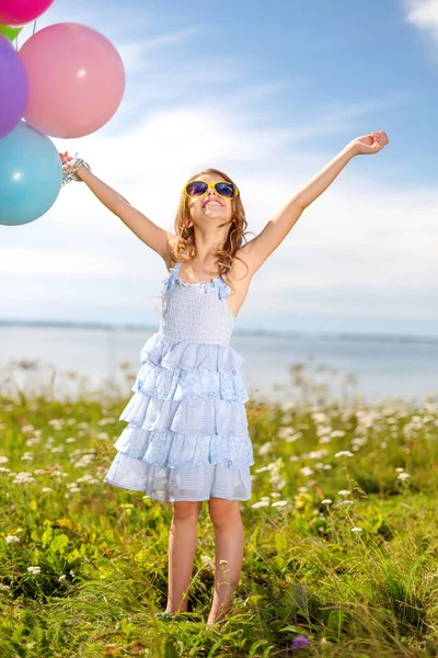 Щаслива дівчина махає руками з різнокольоровими кульками — стокове фото