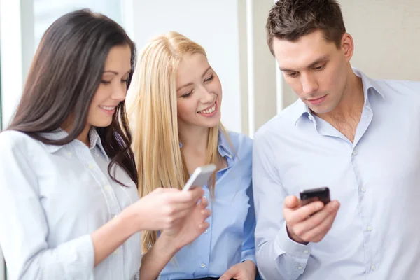 Lächelndes Business-Team mit Smartphones im Büro — Stockfoto