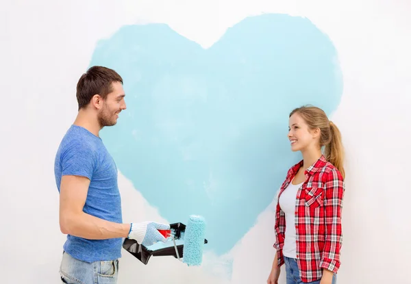 Lachende paar schilderij groot hart op de muur — Stockfoto