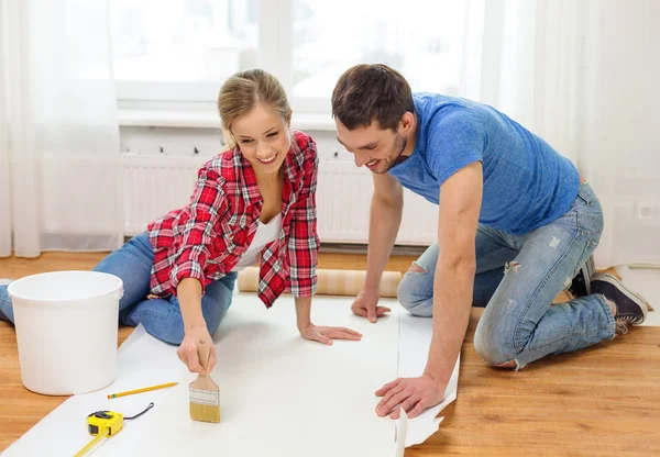 Smiling couple smearing wallpaper with glue — Stock Image Smiling couple smearing wallpaper with glue Royalty Free Stock Images