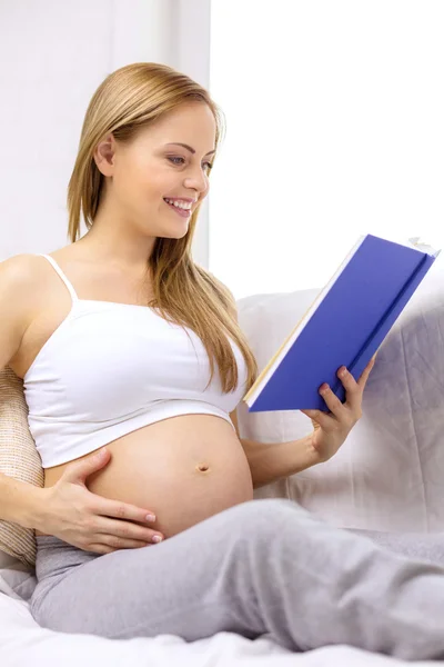 Pregnant woman reading book at home — Stock Photo, Image