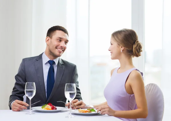 Couple souriant manger plat principal au restaurant — Photo