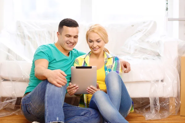 Casal sorridente com tablet pc em nova casa — Fotografia de Stock