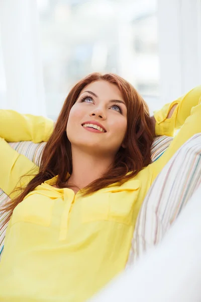 Lächelnde junge Frau liegt zu Hause auf Sofa — Stockfoto