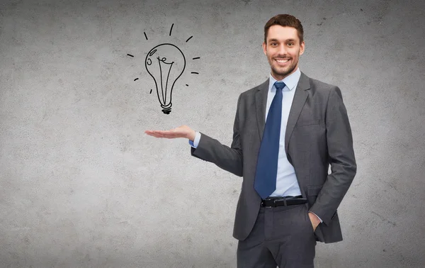 Uomo che mostra lampadina sul palmo della mano — Foto Stock