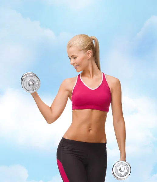Smiling woman lifting steel dumbbell — Stock Photo, Image