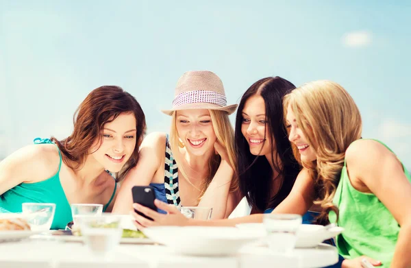 Девушки смотрят на смартфон в кафе на пляже — стоковое фото