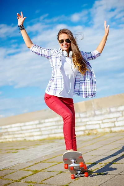 Sonriente adolescente chica montando skate fuera — Foto de Stock