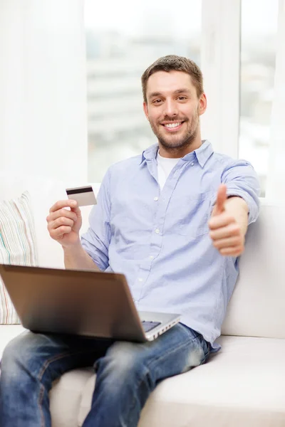 Sorrindo homem trabalhando com laptop e cartão de crédito — Fotografia de Stock