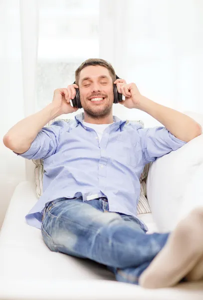 Uśmiechnięty młody mężczyzna w słuchawkach w domu — Zdjęcie stockowe