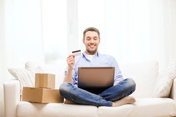 Homme avec ordinateur portable, carte de crédit et boîtes en carton — Photo