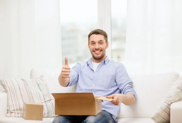 Man with cardboard boxes at home showing thumbs up — Stock Photo, Image