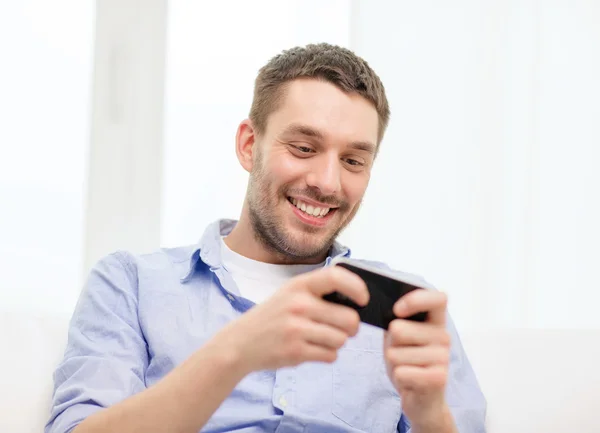 Hombre sonriente con smartphone en casa —  Fotos de Stock