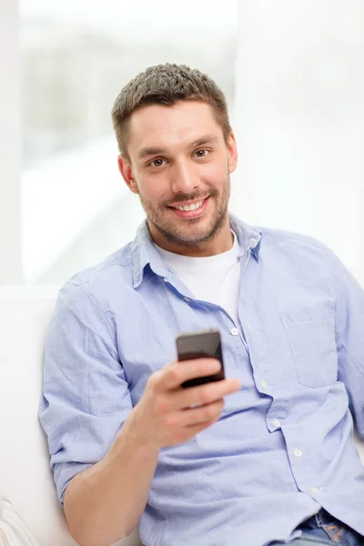 Улыбающийся мужчина со смартфоном дома — стоковое фото