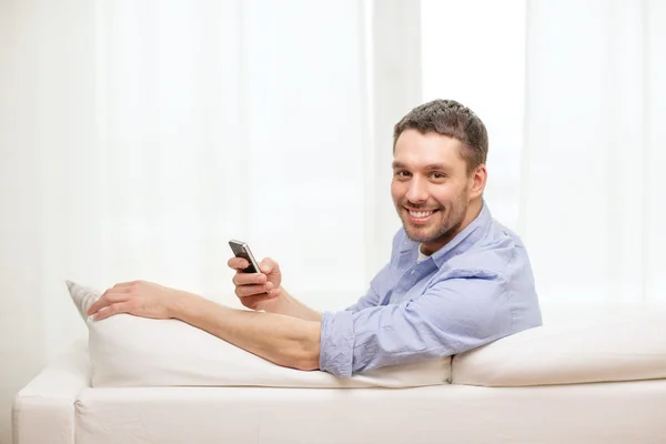 随着智能手机在家里的男人微笑着 — 图库照片