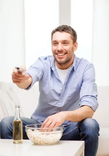 Homme souriant avec télécommande tv à la maison — Photo