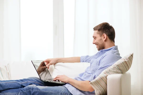 Usmívající se muž pracující s přenosným počítačem doma — Stock fotografie