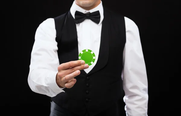 Negociante segurando chip de poker verde — Fotografia de Stock