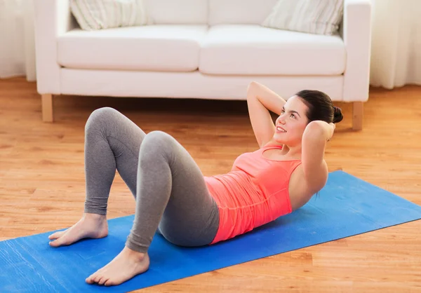 Smiling girl doing exercise on floor at home — Stock Photo, Image