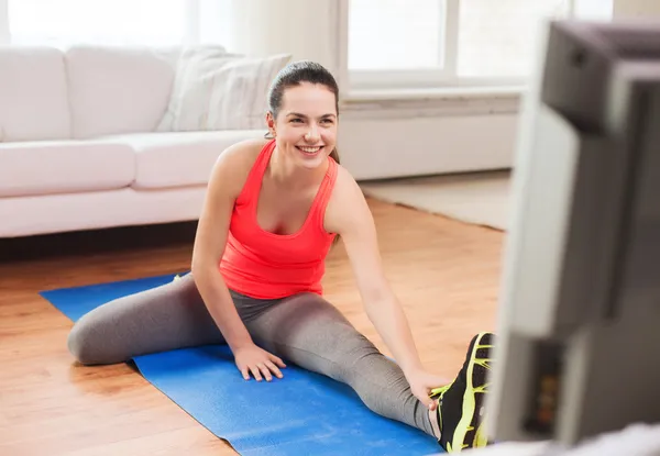 Smiling teenage girl streching on floor at home — Stock Photo, Image