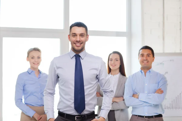 Uomo d'affari sorridente in ufficio con il team sul retro — Foto Stock