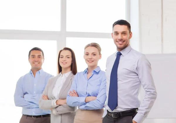 Lächelnder Geschäftsmann im Amt mit Team auf dem Rücken — Stockfoto